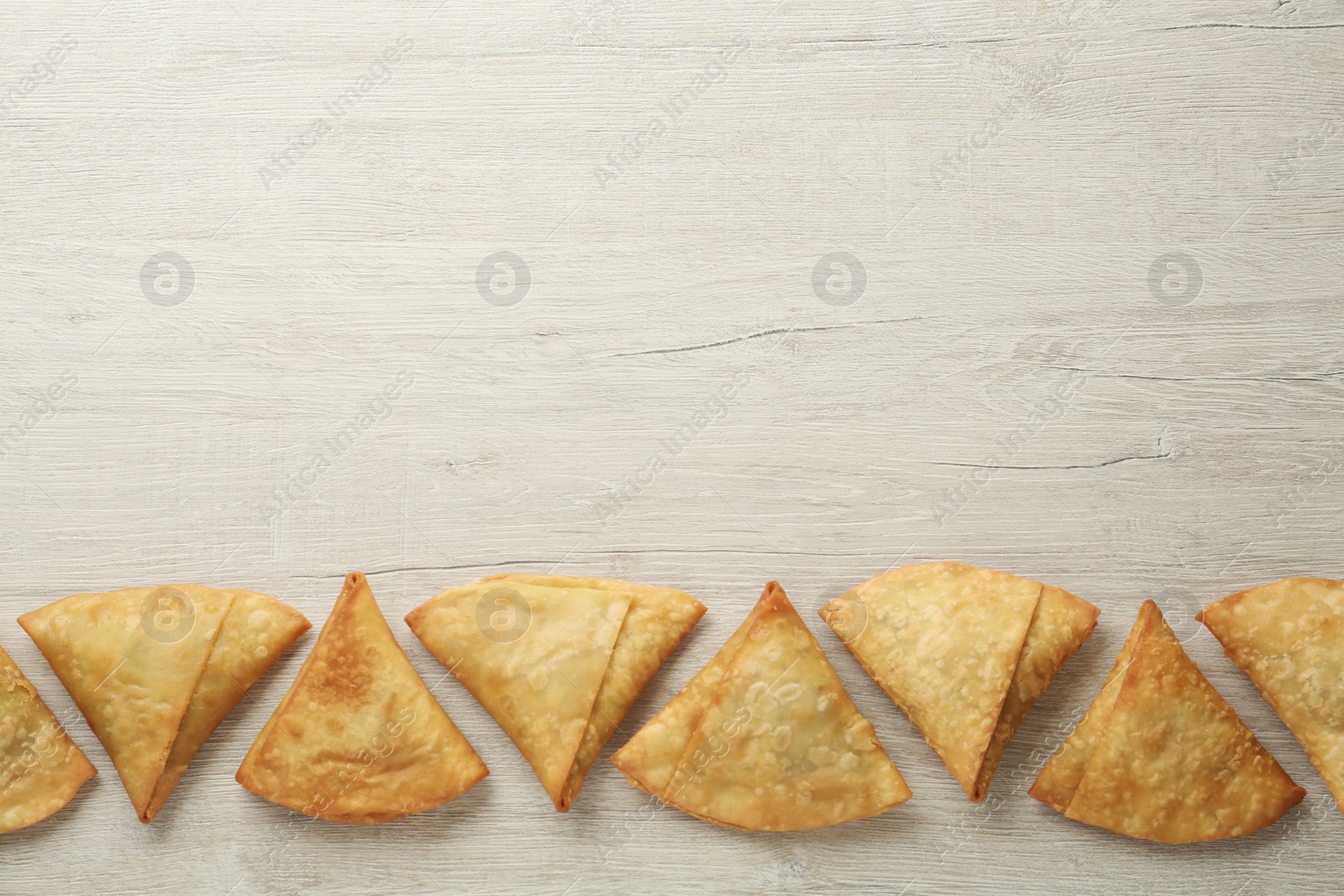 Photo of Fresh delicious crispy samosas on wooden table, flat lay. Space for text