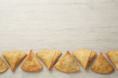 Photo of Fresh delicious crispy samosas on wooden table, flat lay. Space for text