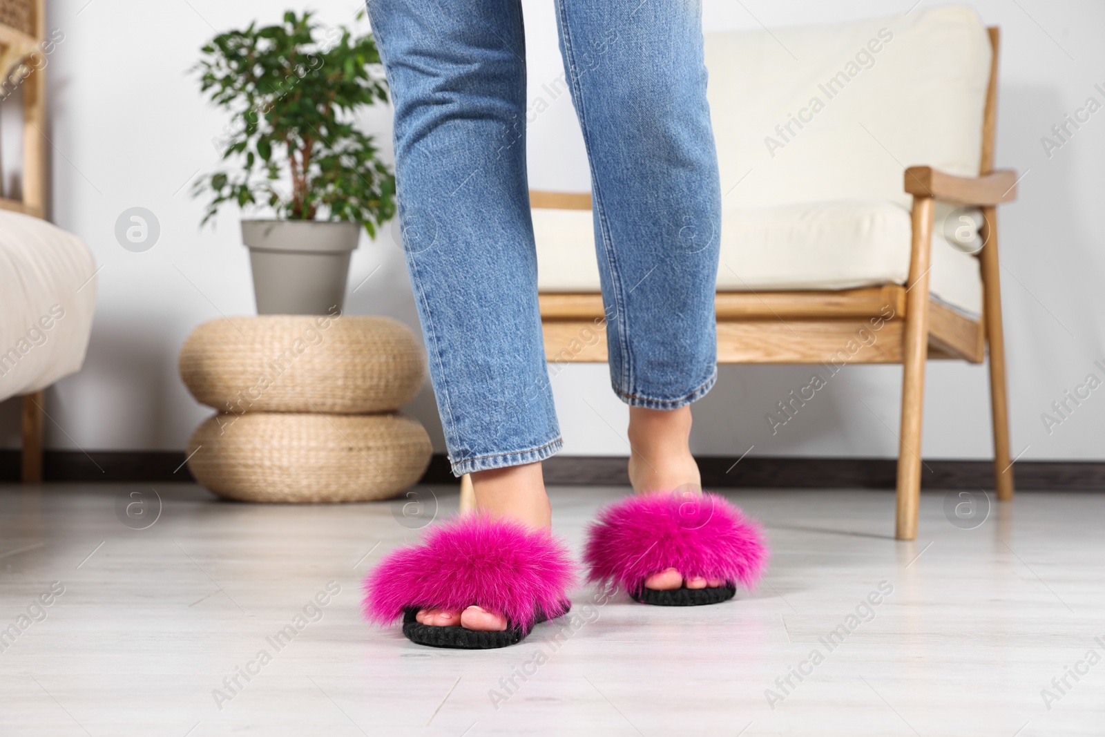 Photo of Woman wearing soft slippers at home, closeup of legs