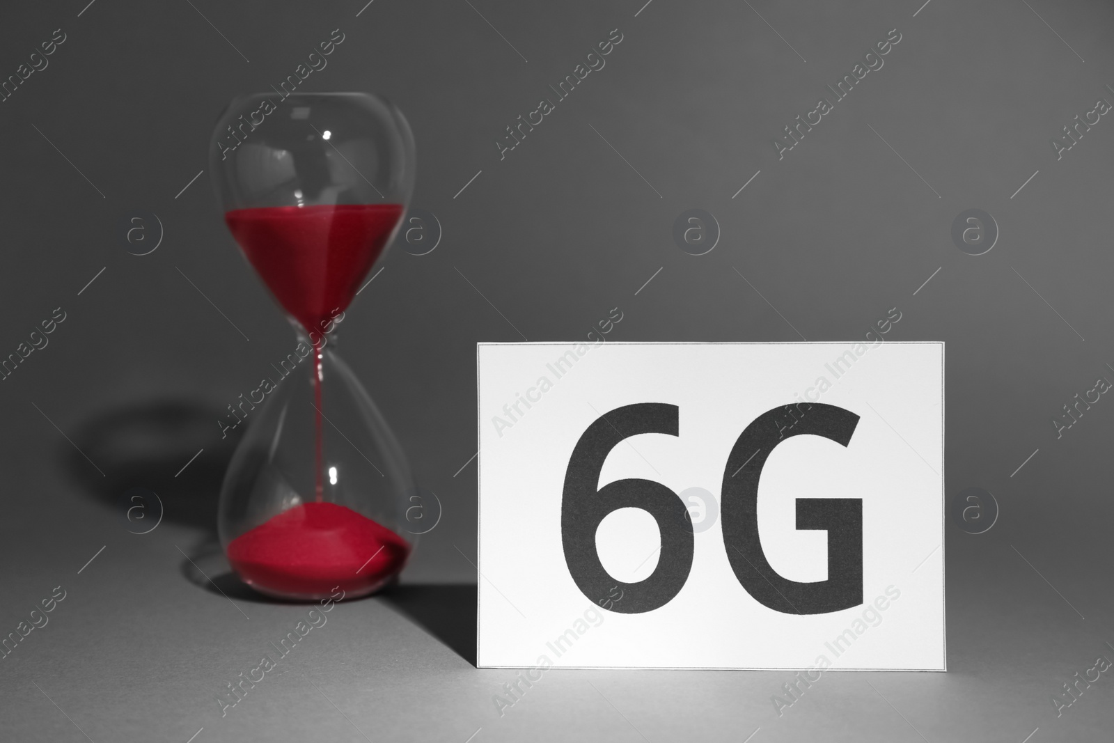 Photo of Internet concept. 6G card and sandglass on grey background