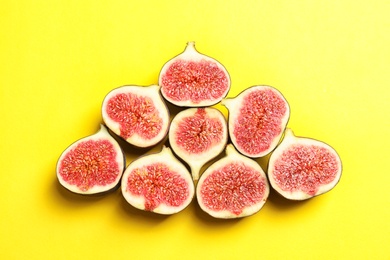 Cut ripe figs on color background, top view