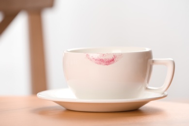 Photo of Ceramic cup with lipstick mark on table indoors