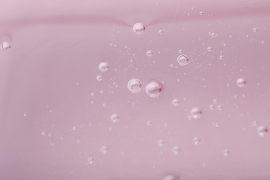 Photo of Pure transparent cosmetic gel on pink background, closeup