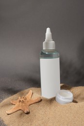 Photo of Cosmetic products and starfish on sand against grey background