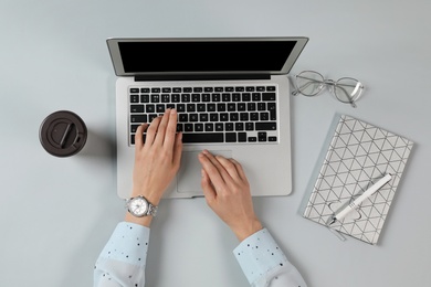 Woman using modern laptop at table, top view