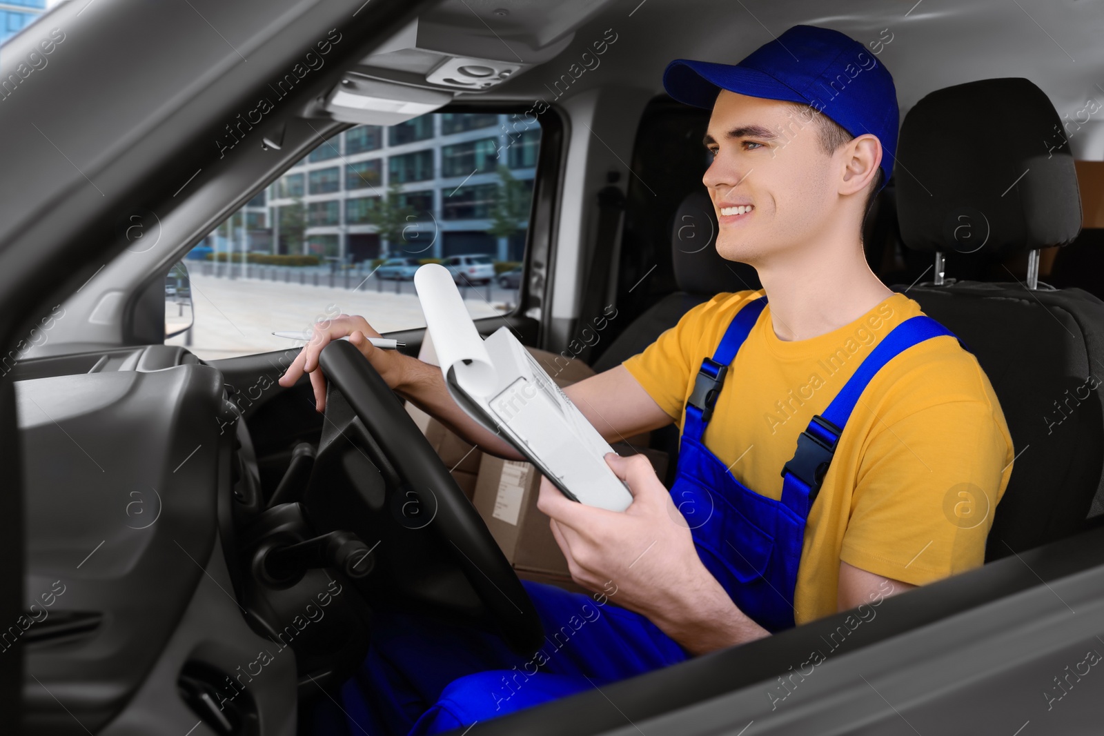 Photo of Courier with clipboard checking packages in car