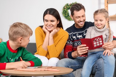 Cute children with their parents making beautiful Christmas greeting cards at home