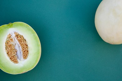 Photo of Whole and cut fresh ripe honeydew melons on teal background, flat lay. Space for text