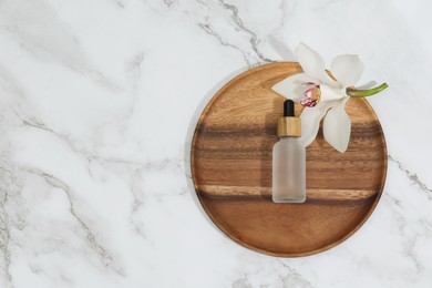 Bottle of cosmetic product and orchid flower on white marble table, top view. Space for text