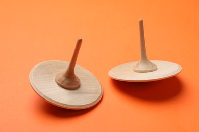 Two wooden spinning tops on orange background