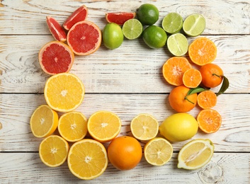 Photo of Frame made of different citrus fruits on wooden background, top view. Space for text