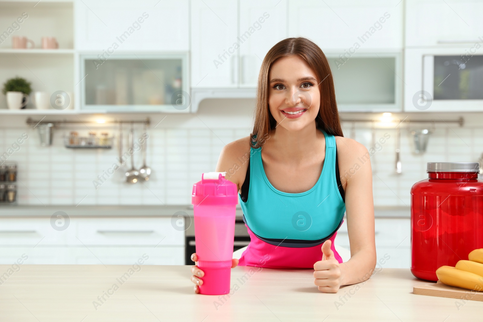 Photo of Young woman with bottle of protein shake in kitchen