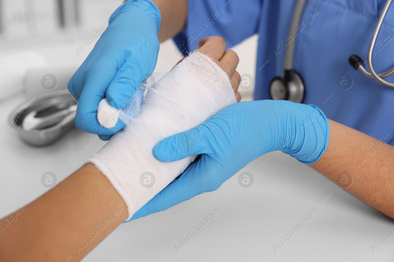 Photo of Doctor bandaging patient's burned hand at table, closeup