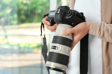 Photo of Male photographer with professional camera on blurred background. Space for text