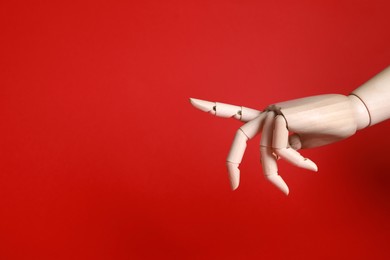 Photo of Wooden mannequin hand on red background. Space for text