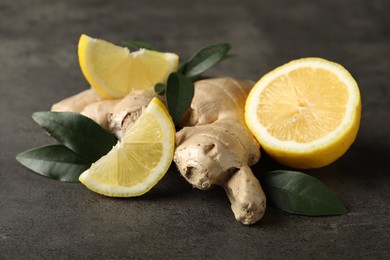 Photo of Fresh lemon and ginger on grey table, closeup