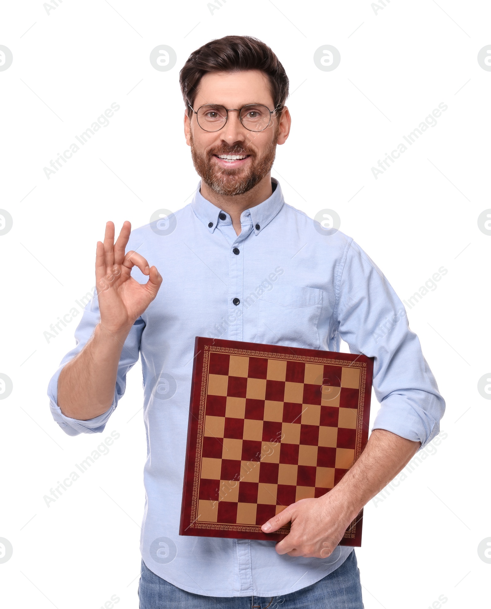 Photo of Smiling man holding chessboard and showing OK gesture on white background