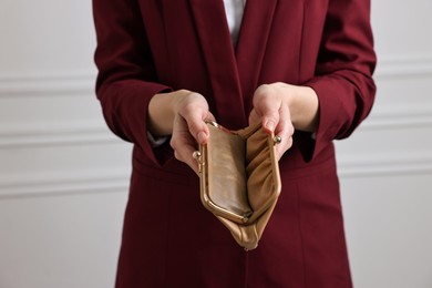 Photo of Woman with empty wallet near white wall, closeup