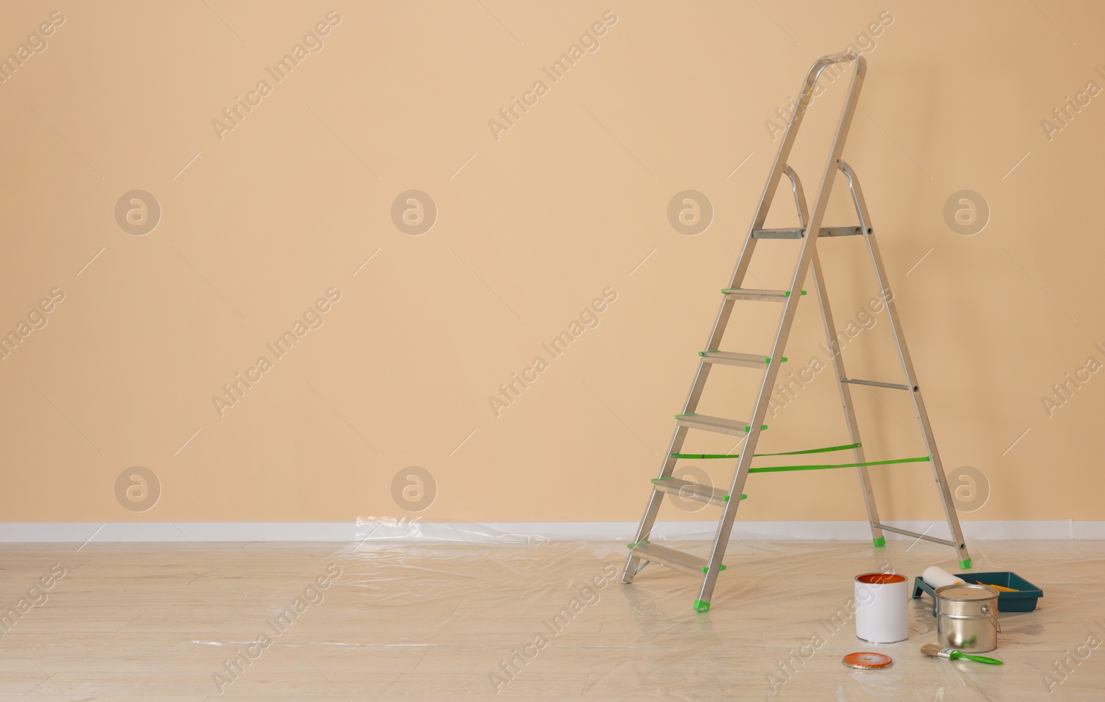 Photo of Metal stepladder near pale orange wall indoors, space for text. Room renovation