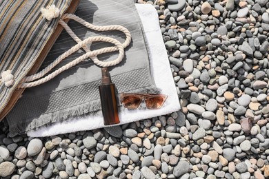 Stylish bag, sunglasses and spray on stones outdoors, flat lay. Space for text