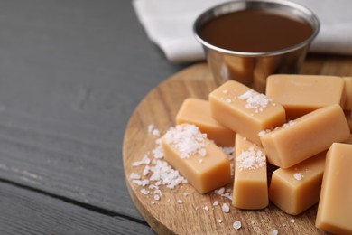 Yummy caramel candies and sea salt on wooden table, closeup. Space for text