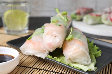 Photo of Delicious spring rolls and soy sauce on table, closeup