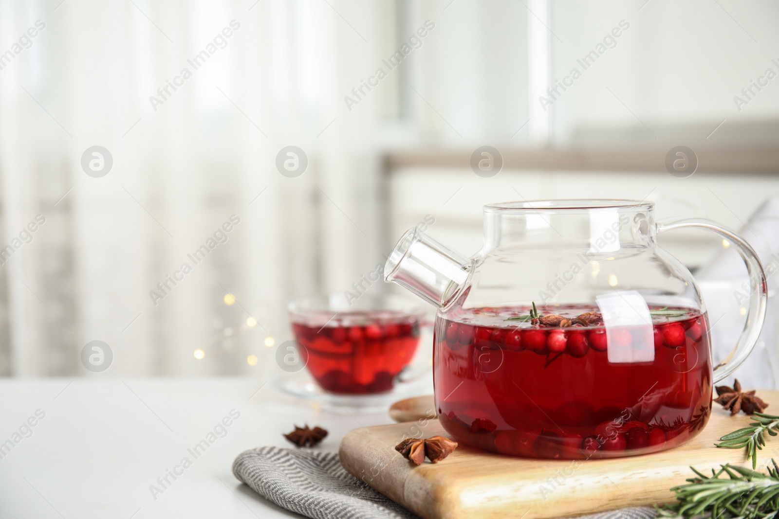 Photo of Tasty hot cranberry tea with rosemary and anise on white table. Space for text