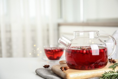 Photo of Tasty hot cranberry tea with rosemary and anise on white table. Space for text