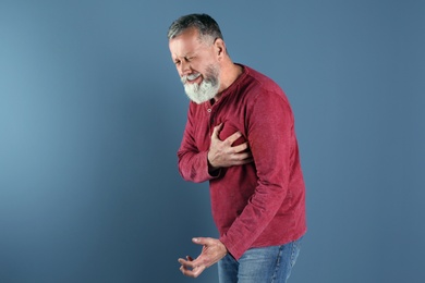 Photo of Mature man having heart attack on color background