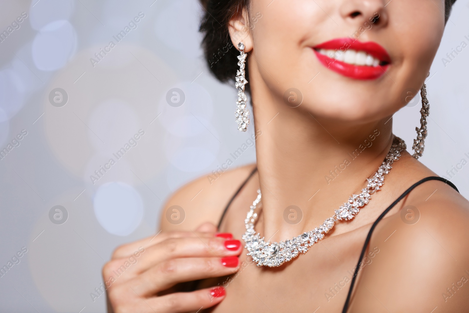 Photo of Beautiful woman with elegant jewelry on blurred background, closeup. Space for text