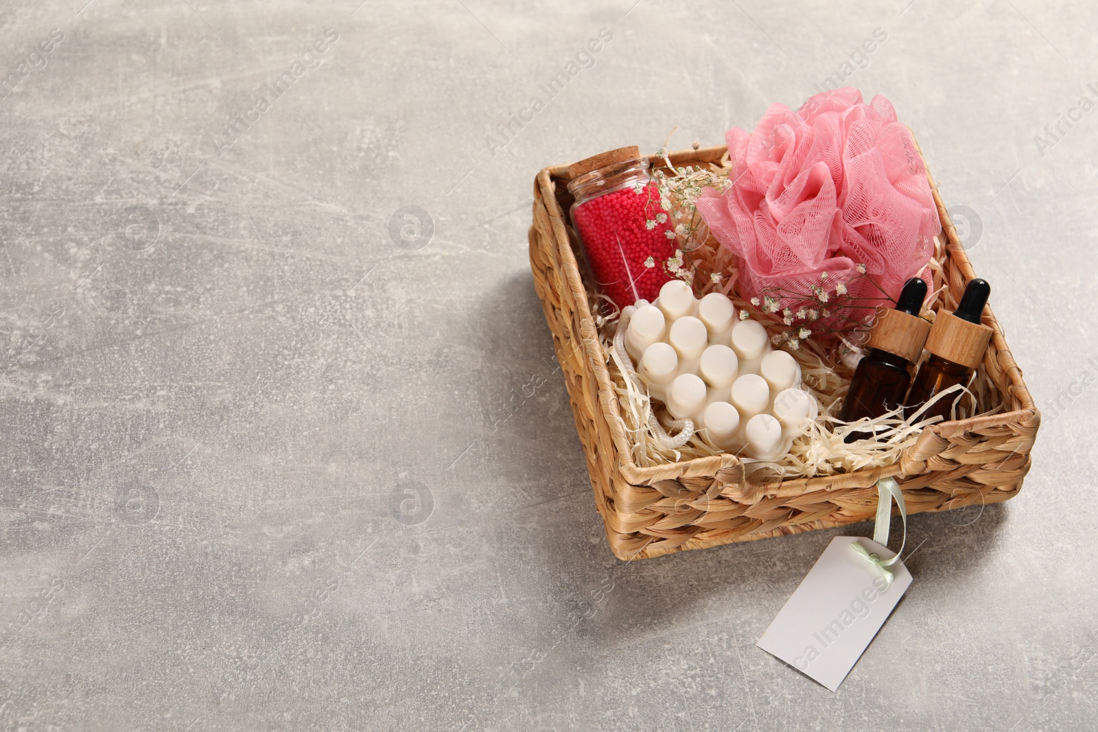 Photo of Spa gift set of different luxury products in wicker basket on grey table, space for text