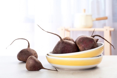 Photo of Bowl with ripe raw beets on table