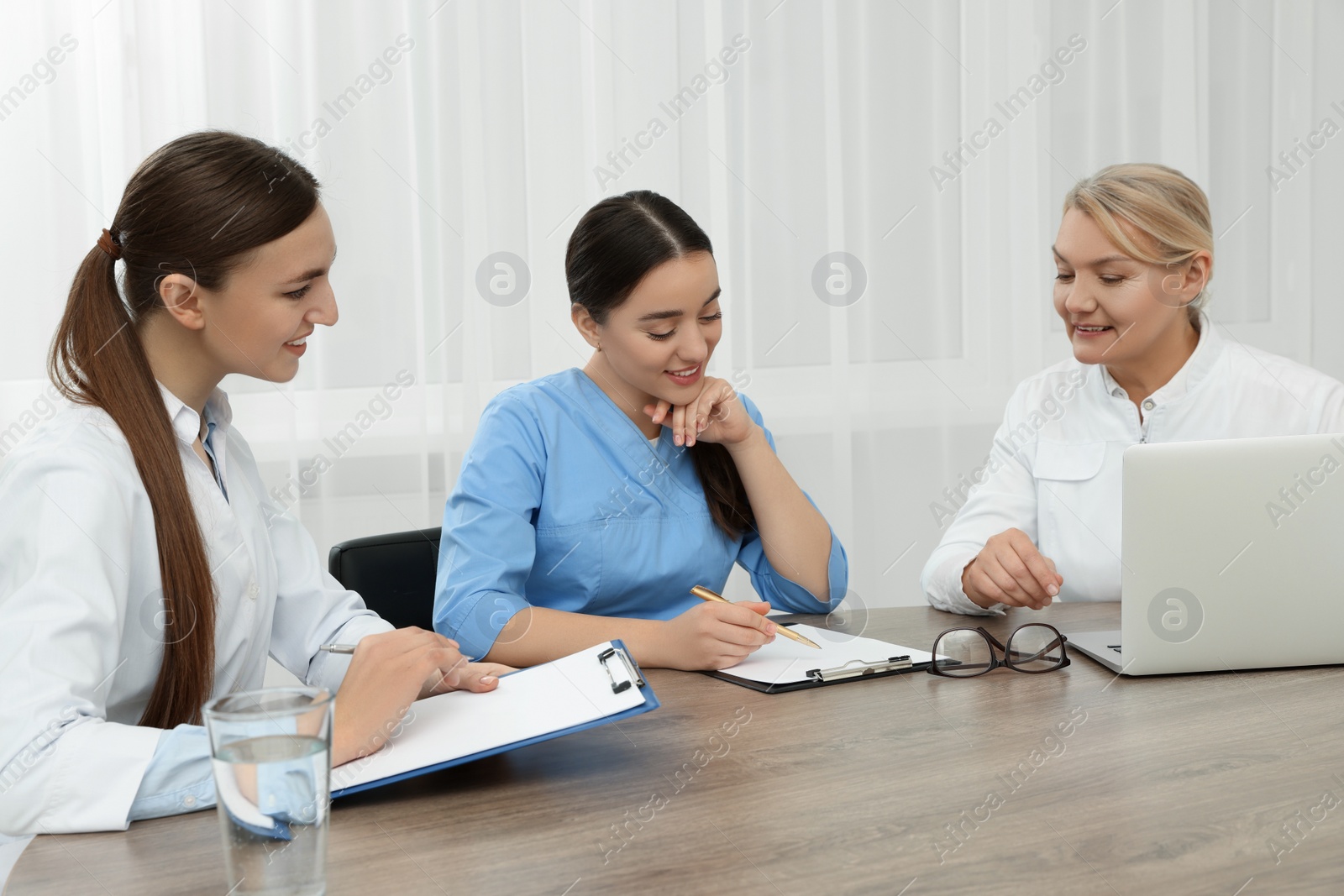 Photo of Medical conference. Doctors working at wooden table in office