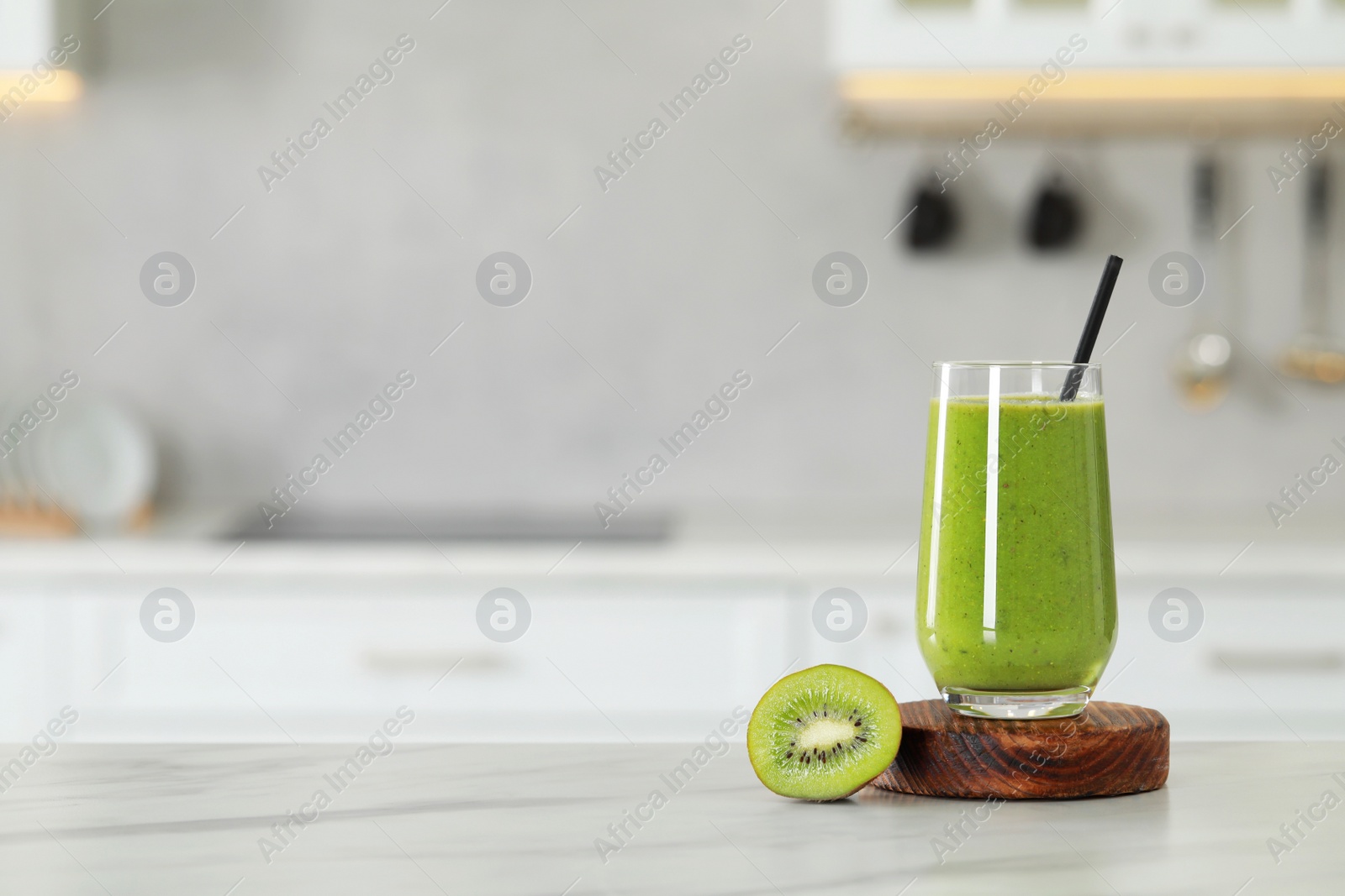 Photo of Glass of fresh smoothie and kiwi on white marble table in kitchen. Space for text