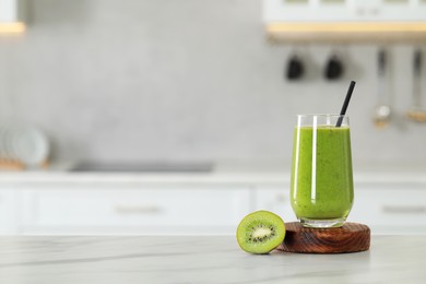 Photo of Glass of fresh smoothie and kiwi on white marble table in kitchen. Space for text
