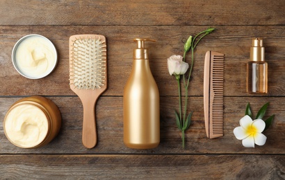Photo of Flat lay composition with hair cosmetic products on wooden table