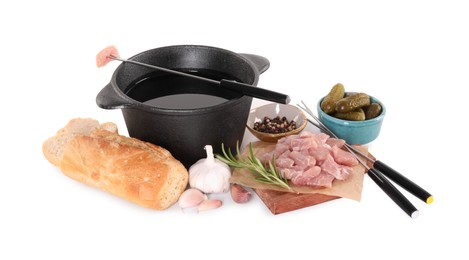 Fondue pot with oil, forks, raw meat pieces and other products isolated on white