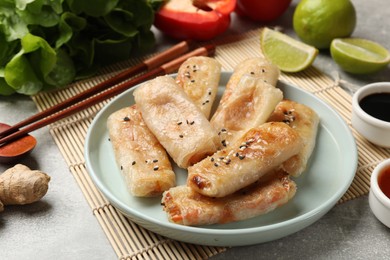 Photo of Tasty fried spring rolls served on gray table, closeup