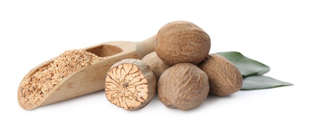 Grated nutmeg and seeds with green leaves on white background