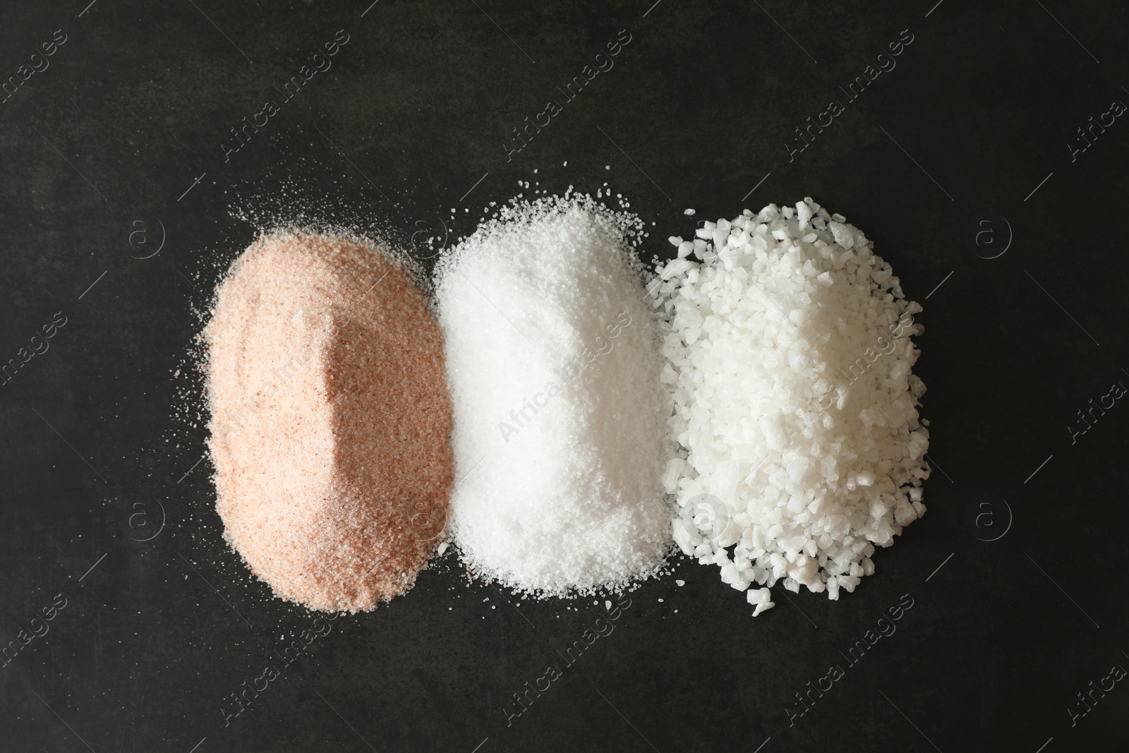 Photo of Different types of organic salt on black table, top view