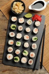 Tasty sushi rolls served on wooden table, flat lay