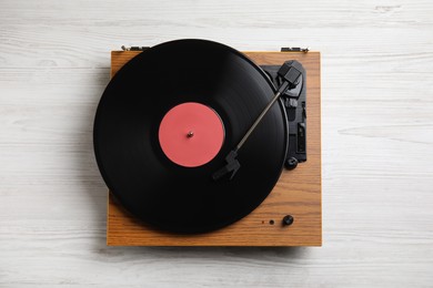 Modern vinyl record player with disc on white wooden background, top view
