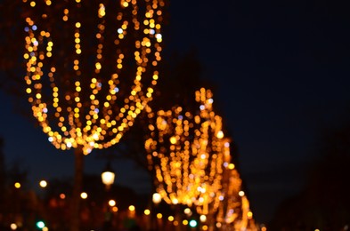 Photo of Blurred view of street with beautiful lights on trees at night. Bokeh effect