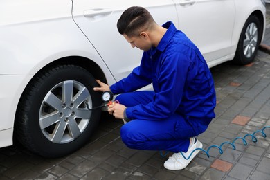 Professional mechanic inflating tire at car service