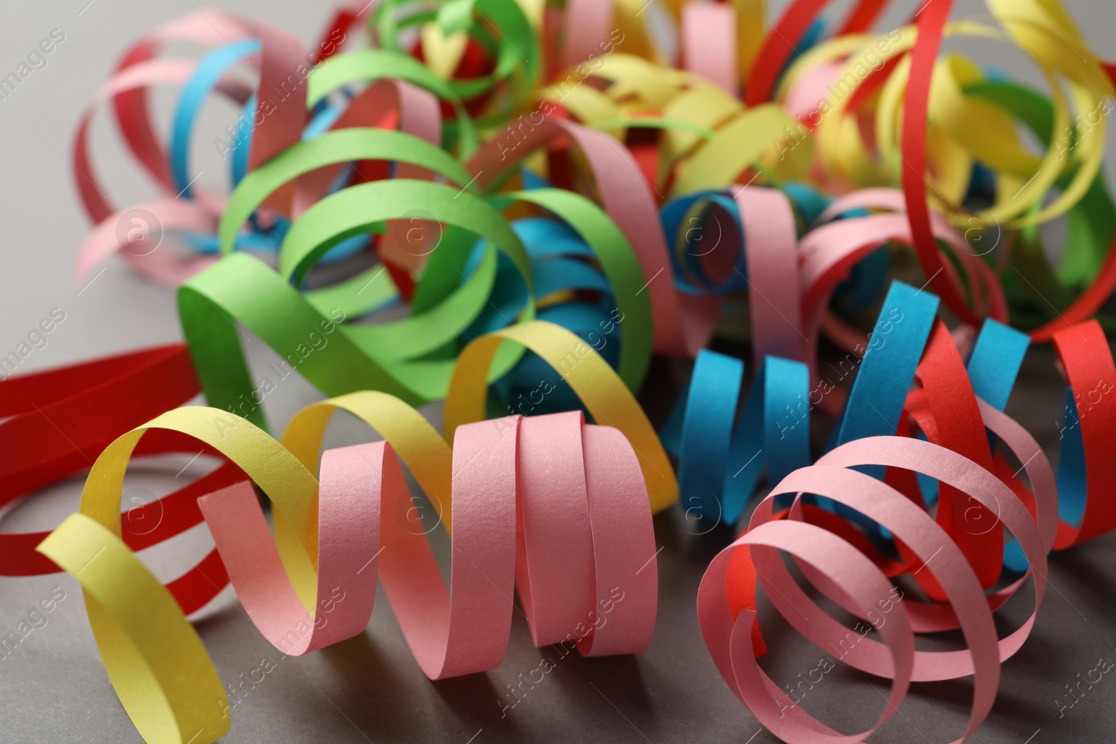 Photo of Colorful serpentine streamers on grey background, closeup