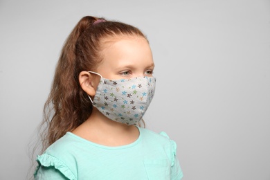 Photo of Preteen girl in protective face mask on light grey background