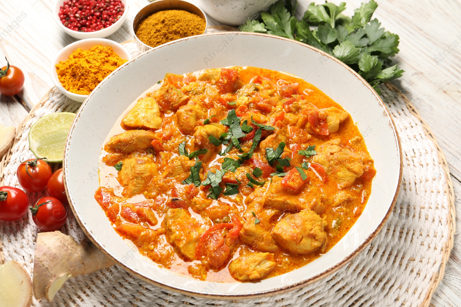 Photo of Delicious chicken curry and ingredients on wooden table