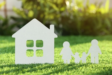 Paper cutout of family and house on fresh grass. Life insurance concept