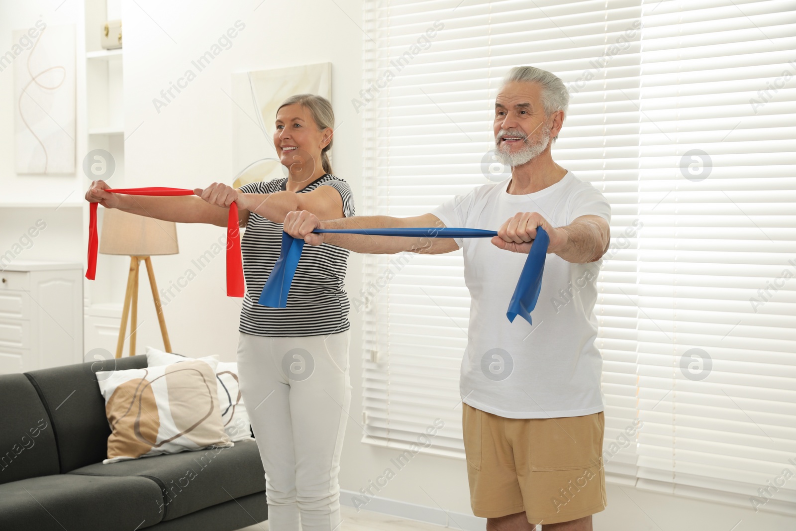 Photo of Senior couple doing exercise with fitness elastic bands at home