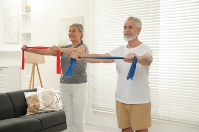 Senior couple doing exercise with fitness elastic bands at home